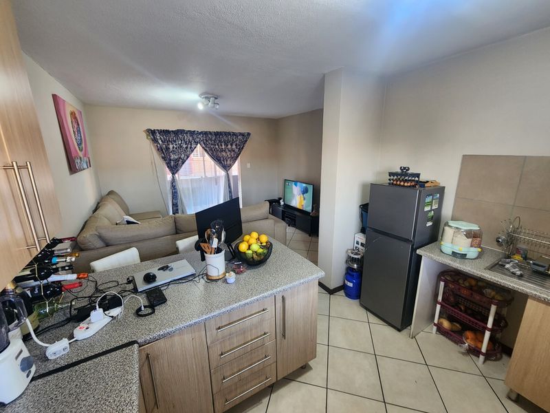 Open-plan living area featuring a functional kitchen with granite countertops and tiled flooring, seamlessly connecting to the adjacent lounge space.
