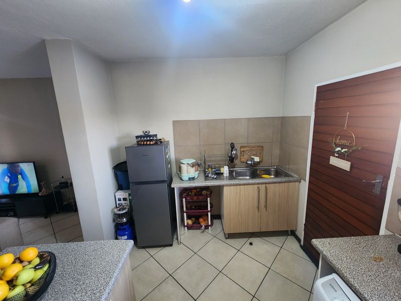 A compact kitchen area featuring a double bowl sink, tiled splashback, and laminate cabinetry with granite-look countertops.