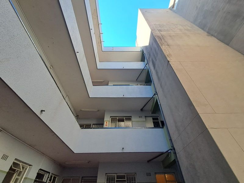 Low-angle view of an apartment building's central atrium and exterior facade, showing multi-level walkways and concrete structure.
