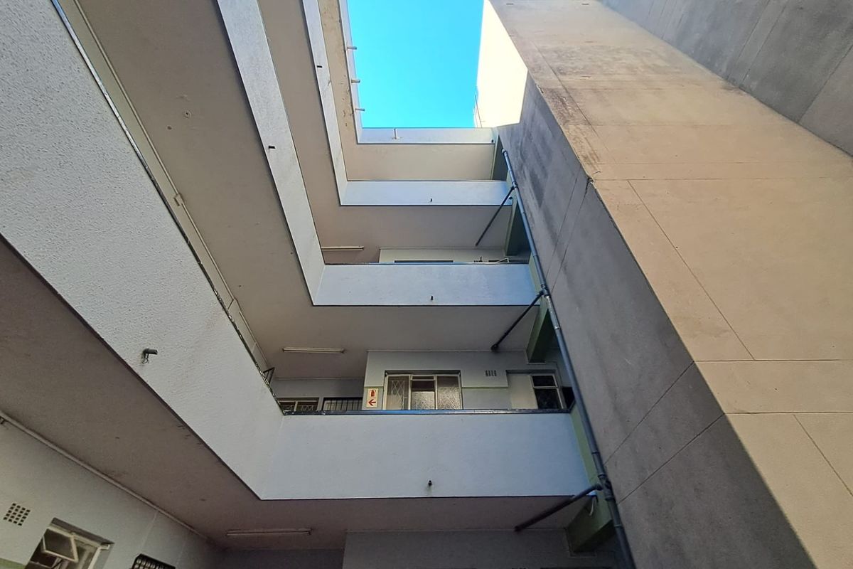 Low-angle view of an apartment building's central atrium and exterior facade, showing multi-level walkways and concrete structure.