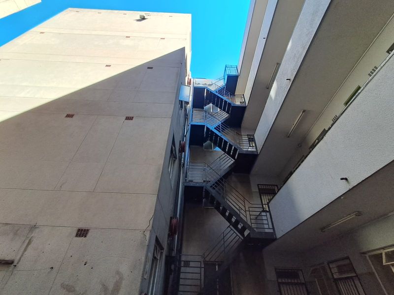 View of the apartment building exterior featuring a metal fire escape staircase and concrete facade.