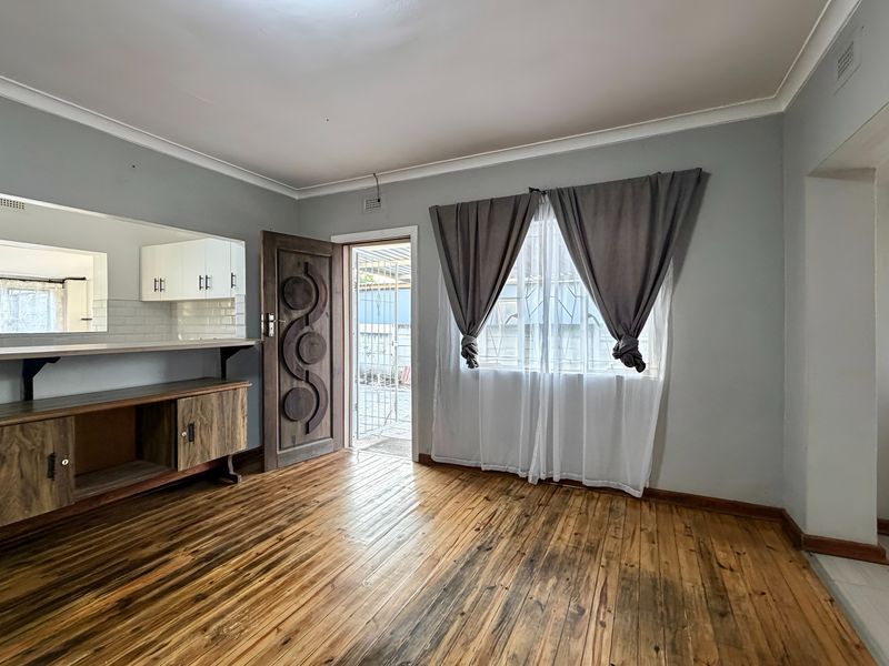 Open plan living area featuring hardwood flooring, built-in cabinetry, and a breakfast bar, with direct access to the exterior via a security gate.