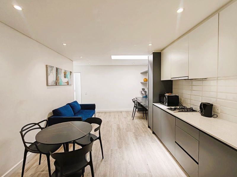 Modern open-plan apartment featuring a sleek kitchen with stone countertops, gas hob, and integrated cabinetry, flowing into a functional living and dining area.
