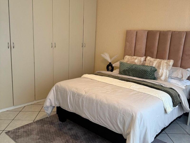 A bedroom featuring tiled flooring, a ceiling fan, and extensive built-in cupboard storage.