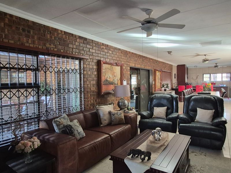 Spacious open-plan living area featuring exposed brick walls, tiled flooring, ceiling fans, and sliding door access to the exterior.