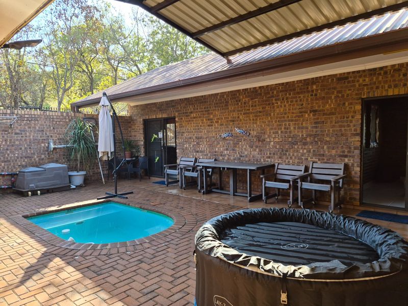 A covered outdoor patio area featuring brick paving, an exposed brick wall, and a built-in swimming pool, ideal for outdoor entertaining.