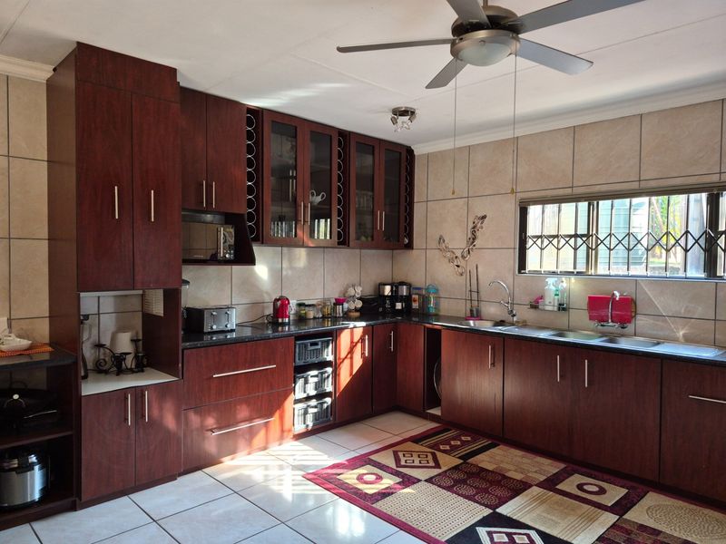 A functional kitchen featuring dark wood cabinetry, granite countertops, a double stainless steel sink, and tiled wall finishes.