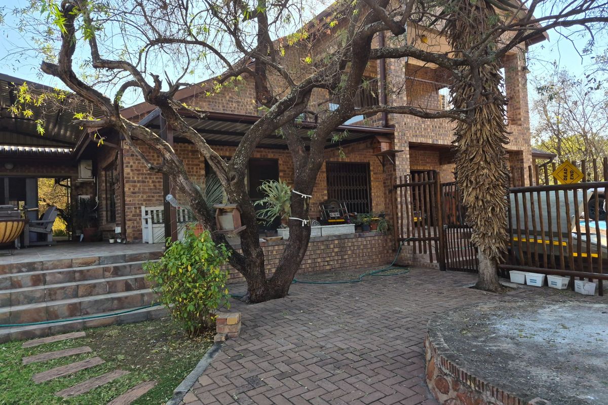 Rear view of a face brick house featuring a paved patio area, covered veranda, and established garden landscaping.