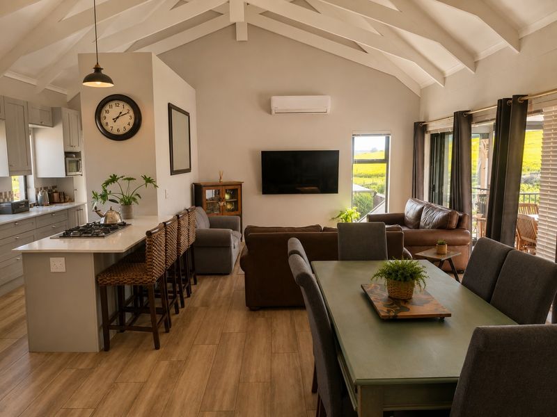 Spacious open-plan living area featuring a modern kitchen with island, vaulted ceilings with exposed beams, and seamless flow to the outdoor patio.