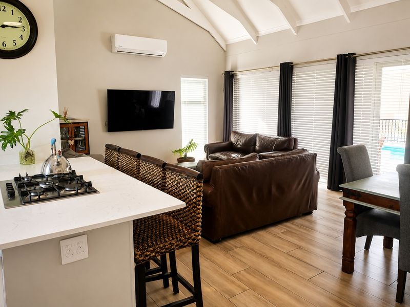 Spacious open-plan living area featuring a modern kitchen island with gas cooktop, vaulted ceilings, and direct access to the outdoor pool area.