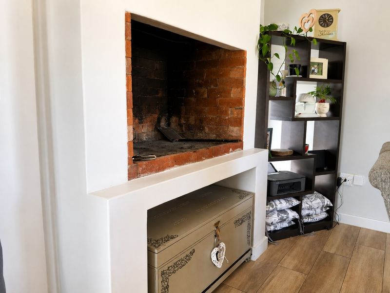 A cozy living room area featuring a built-in fireplace with an exposed brick interior and modern laminate flooring.