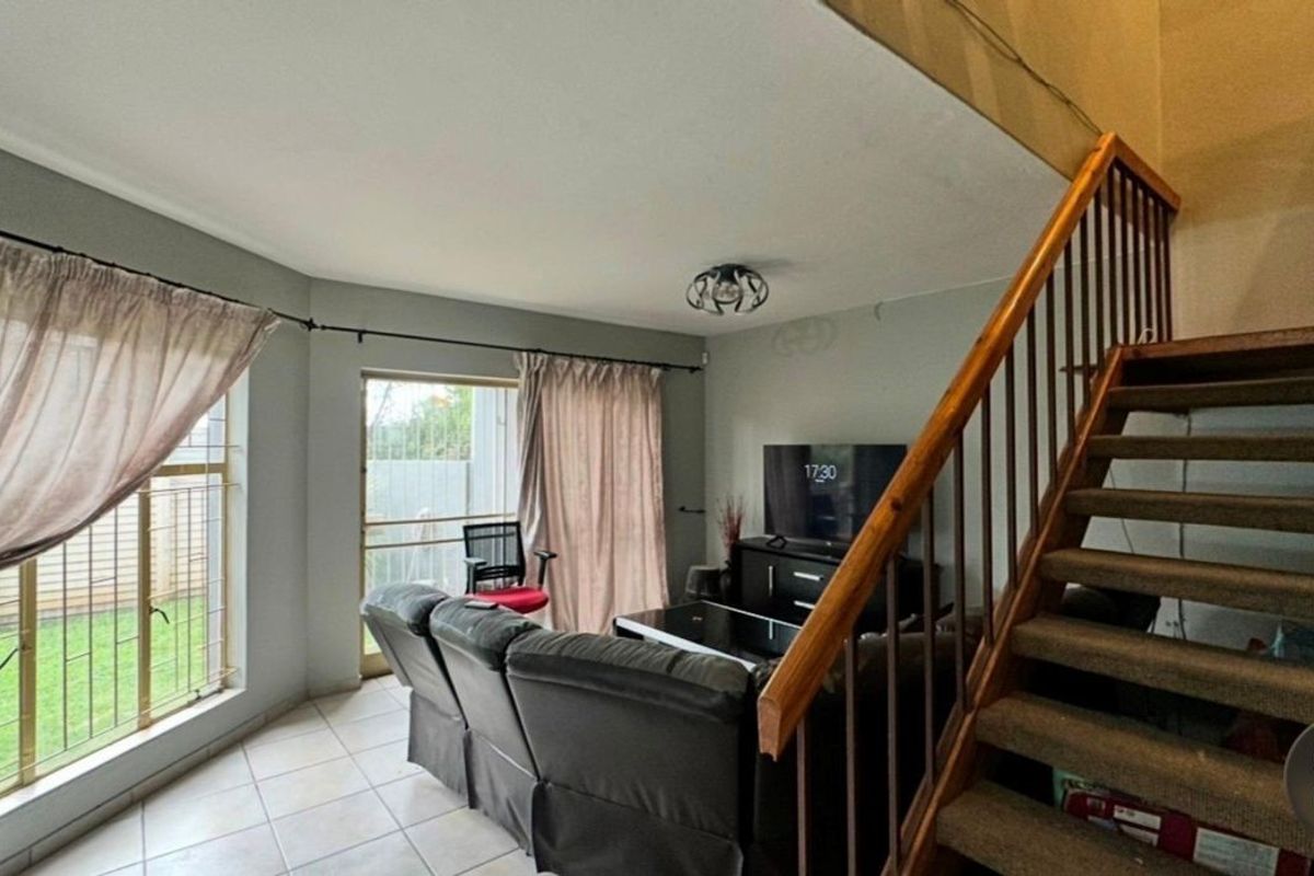 Living room featuring tiled flooring, a staircase with a wooden handrail, and sliding glass doors providing access to the exterior.