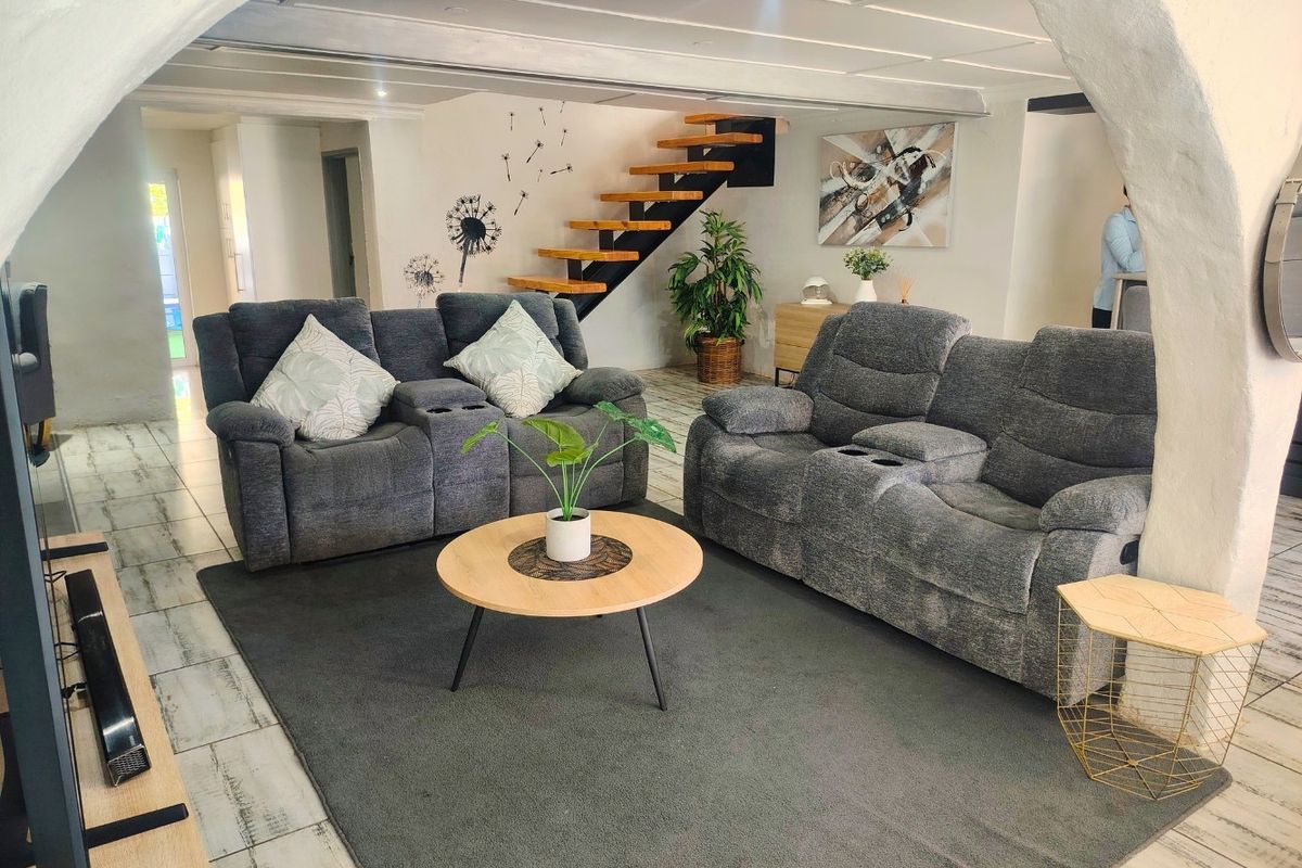 Spacious living area featuring a modern floating staircase, tiled flooring, and a distinctive arched entryway, creating an open and inviting atmosphere.