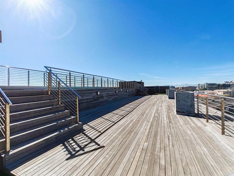 Spacious rooftop terrace featuring timber decking, stainless steel railings, and elevated views, providing an expansive outdoor entertainment area.