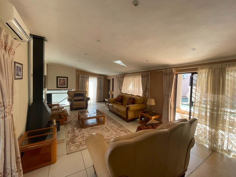 Spacious living room featuring tiled floors, a freestanding fireplace, and large sliding glass doors providing direct access to the outdoor pool area.