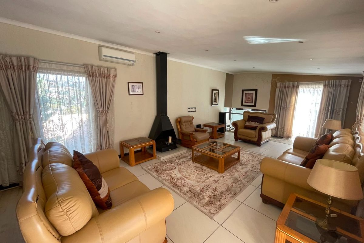 Spacious living room featuring tiled flooring, a central freestanding fireplace, and a wall-mounted air conditioning unit with ample natural light.