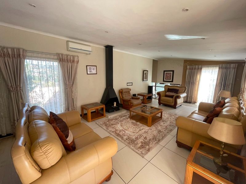Spacious living room featuring tiled flooring, a central freestanding fireplace, and a wall-mounted air conditioning unit with ample natural light.