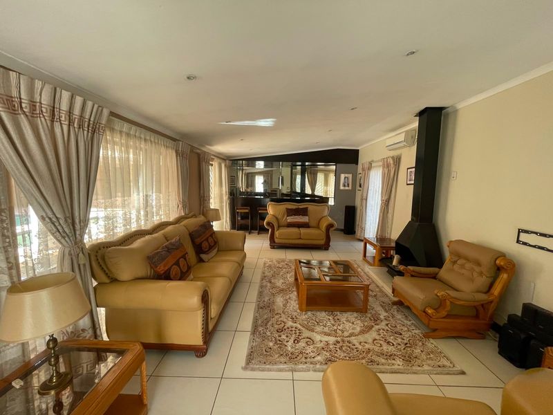 Spacious living room featuring tiled flooring, a modern black fireplace, and a built-in bar area, offering a comfortable and functional layout.