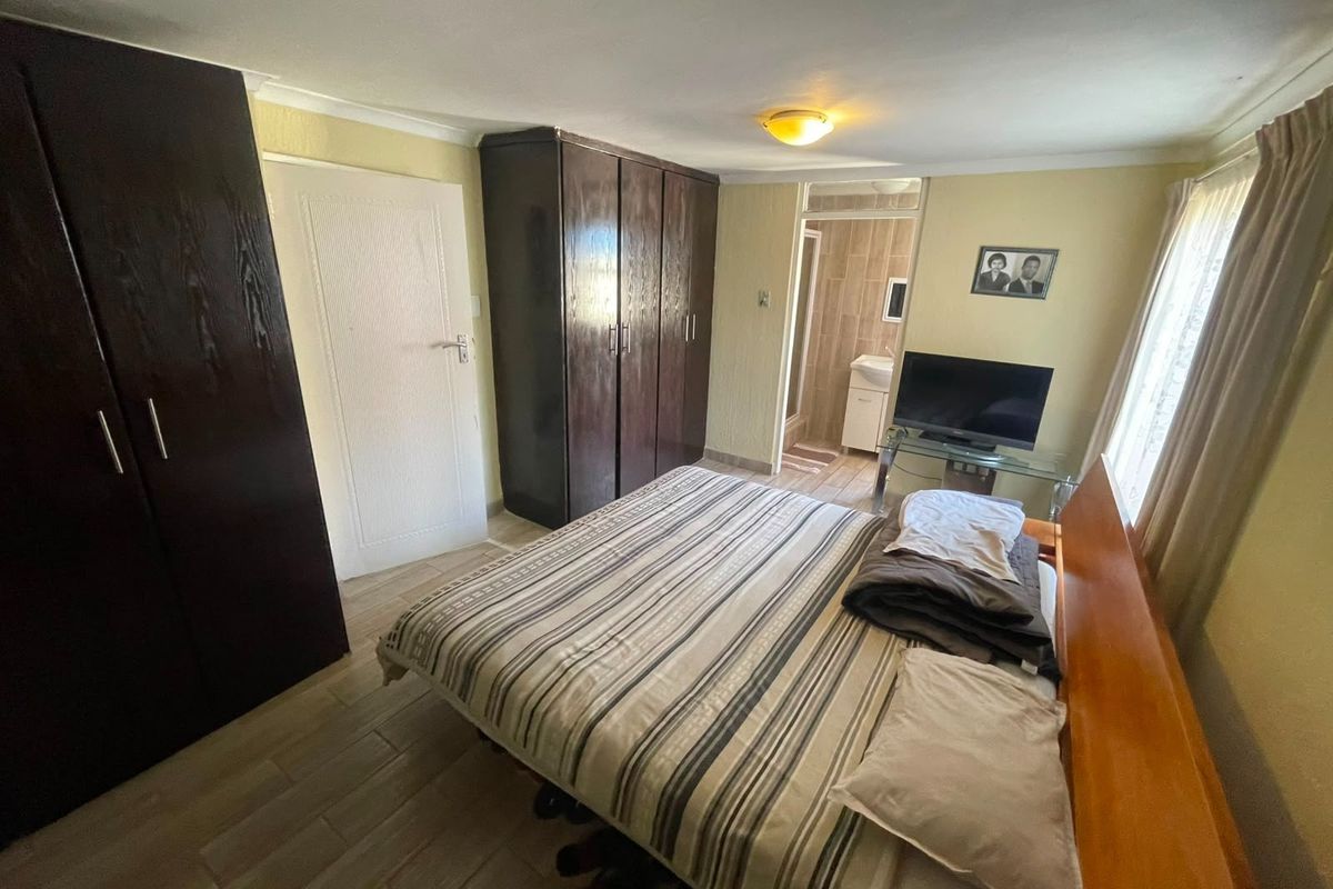 A bedroom featuring built-in cupboards, tiled flooring, and direct access to an en-suite bathroom.