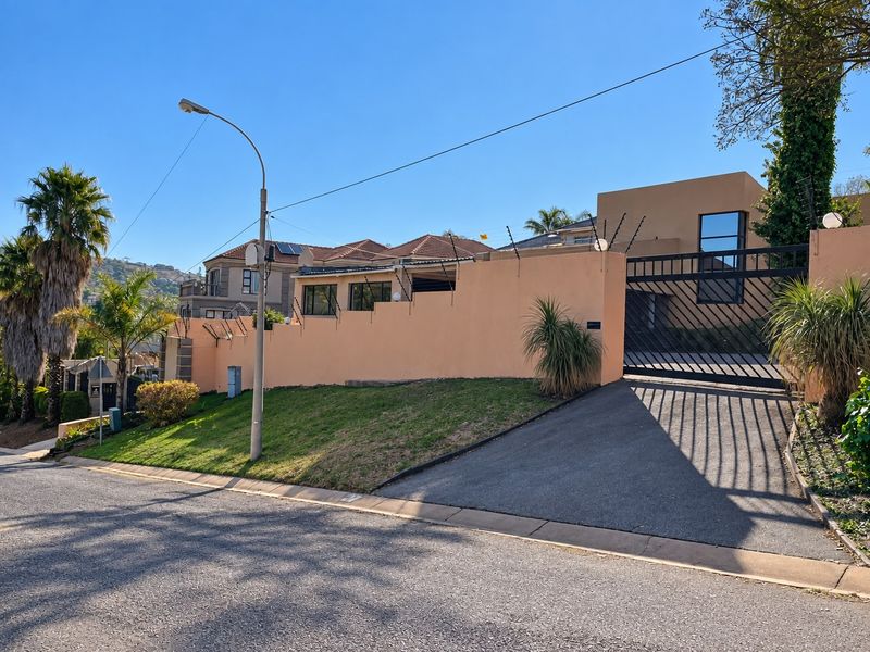 Front exterior view of the property featuring a secure perimeter wall with electric fencing and a private sliding driveway gate.