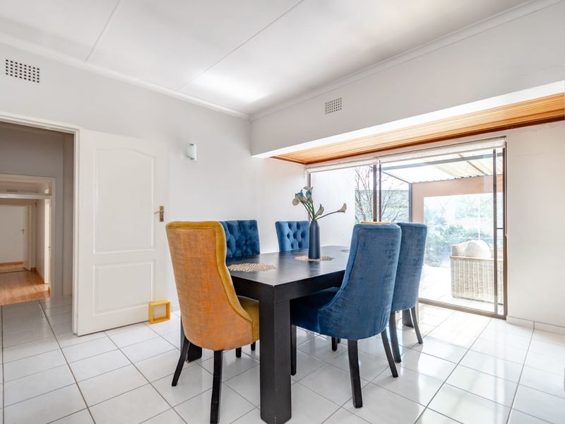 Bright dining area featuring white tiled flooring and large sliding glass doors providing natural light and access to the outdoor patio.