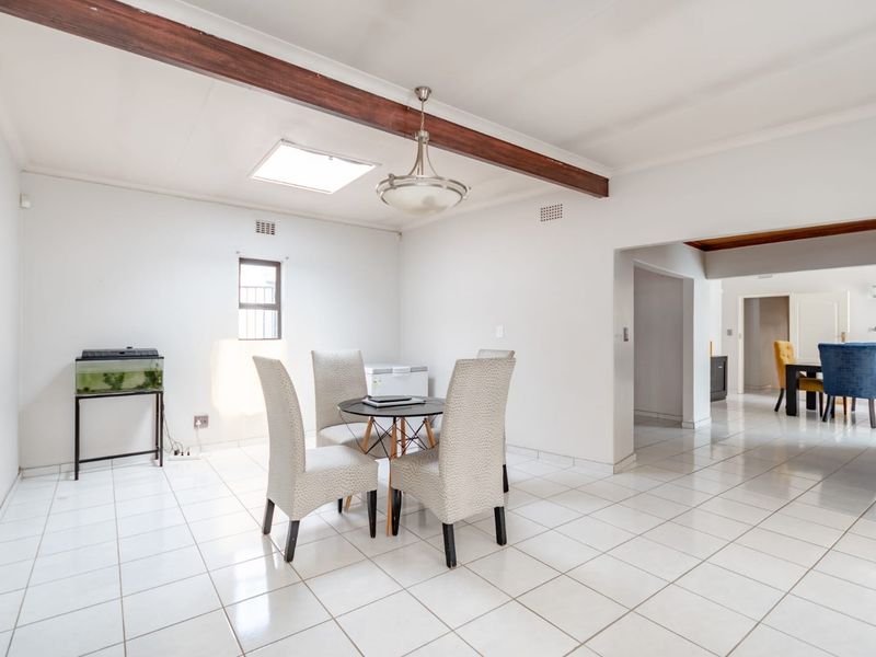 Bright dining area featuring ceramic floor tiles, an exposed timber ceiling beam, and a skylight, providing an open and airy atmosphere.