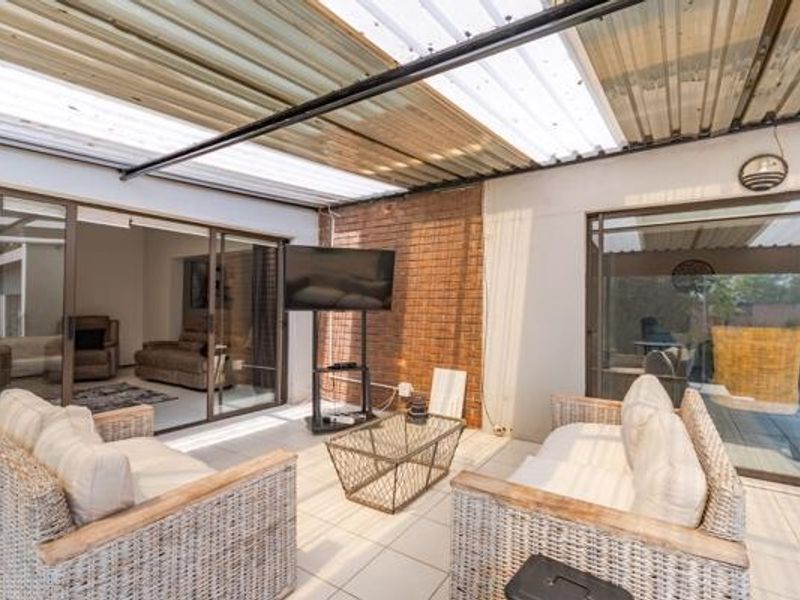A covered patio area featuring tiled flooring, an exposed brick feature wall, and sliding glass doors providing access to the interior living spaces.