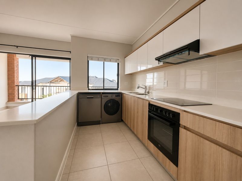 Modern kitchen featuring sleek wood-tone and white cabinetry, stone countertops, integrated appliances, and direct access to a balcony area.