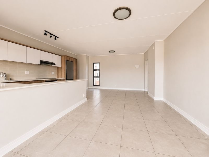 A bright and spacious open-plan living and kitchen area featuring modern cabinetry, tiled flooring, and clean neutral finishes throughout.