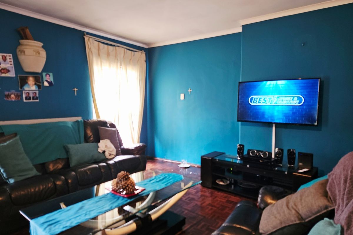 A living room featuring dark parquet flooring and blue painted walls, providing a functional space for relaxation and entertainment.