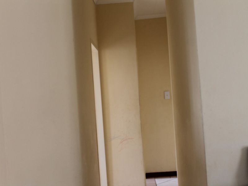 A narrow interior hallway with plain walls and a light switch, showing signs of wear and surface markings.