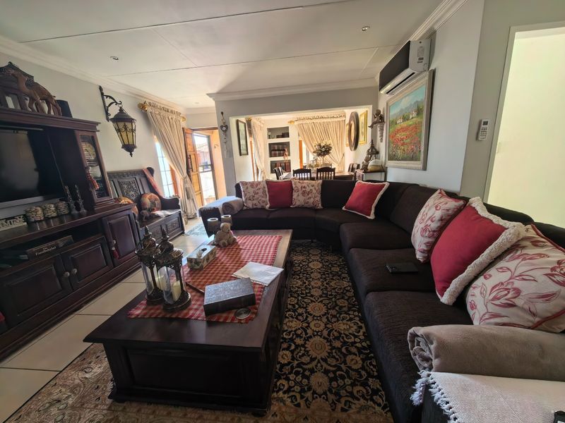 Spacious open-plan living area featuring tiled flooring, recessed lighting, and a wall-mounted air conditioning unit, with an adjacent dining space visible.