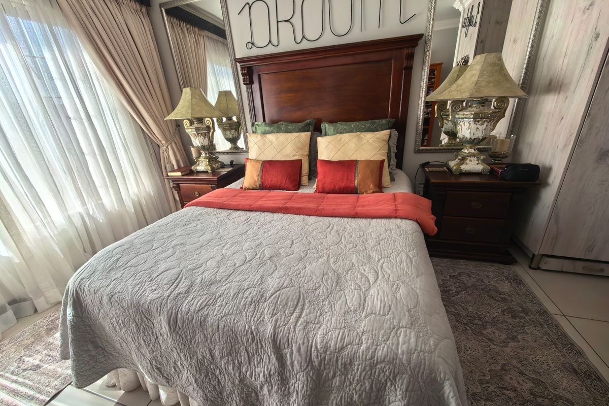 A well-maintained bedroom featuring tiled flooring, built-in wardrobe storage, and large windows with curtain treatments.