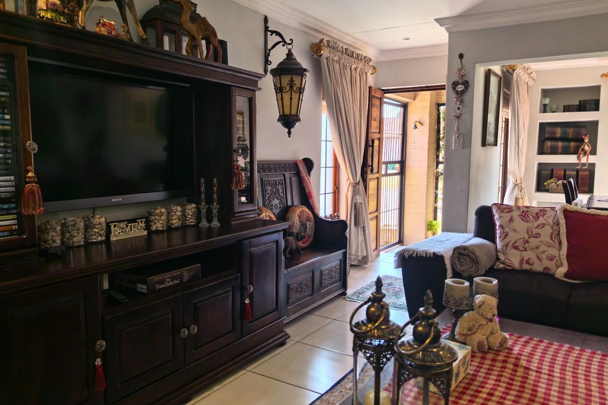 A cozy living room featuring tiled flooring, coved cornicing, and built-in shelving, with direct access to an outdoor area.