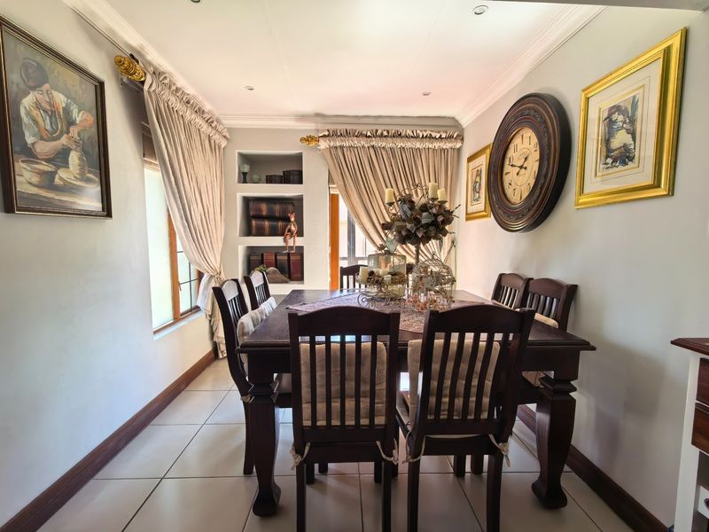 A well-maintained dining room featuring tiled flooring, crown molding, recessed lighting, and built-in recessed shelving.