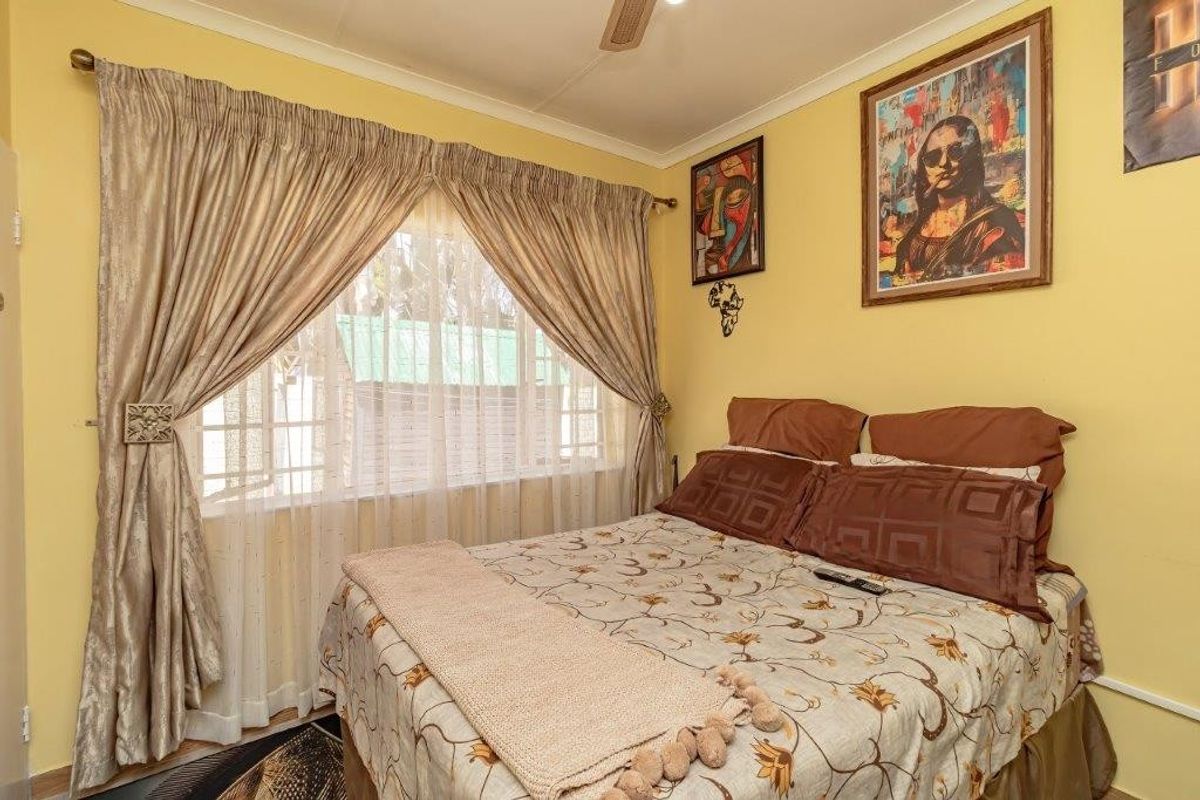 A standard bedroom featuring a ceiling fan and large window with curtain rails, providing natural light and ventilation.