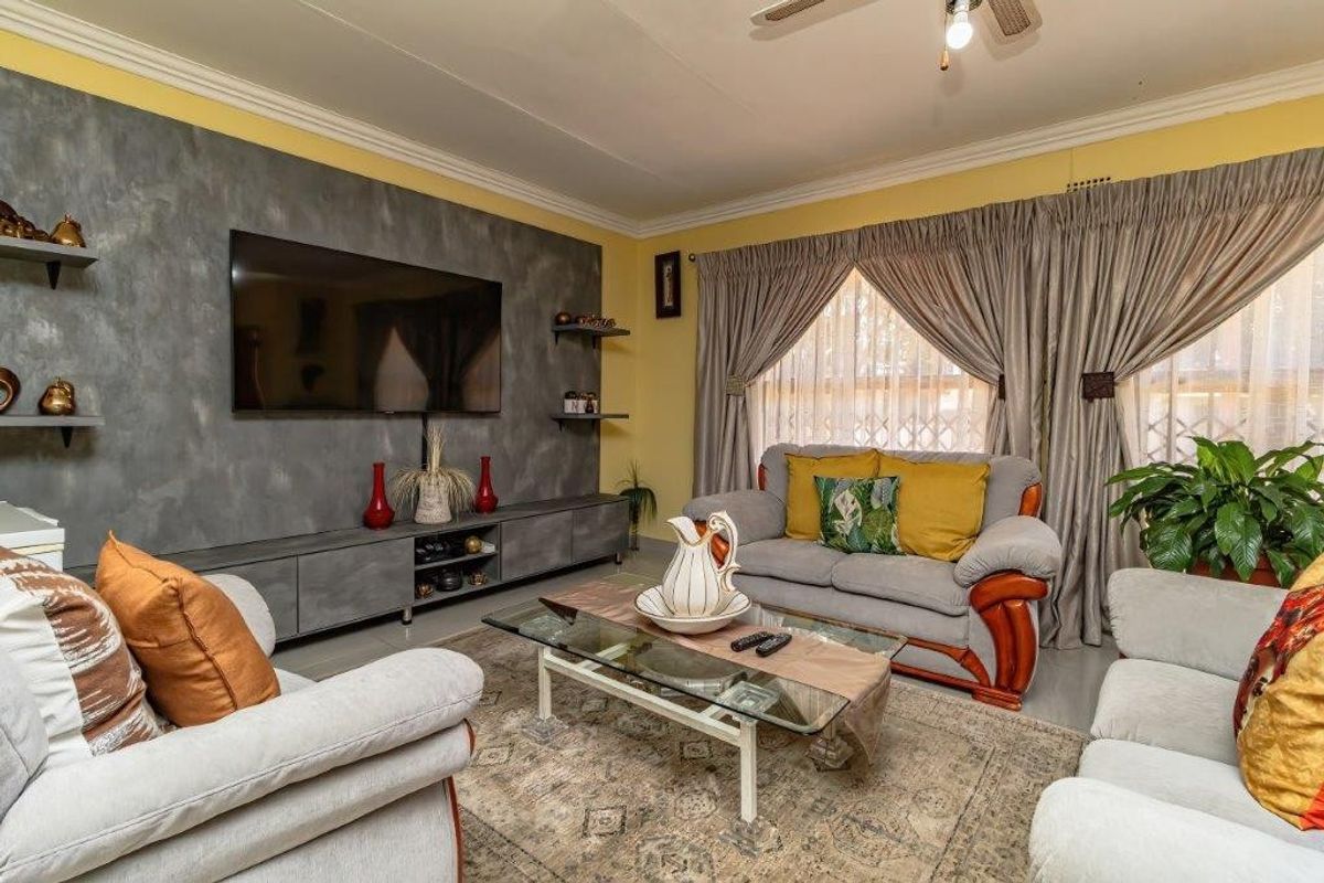 A comfortable living room featuring a textured feature wall with a built-in media console and ceiling fan.