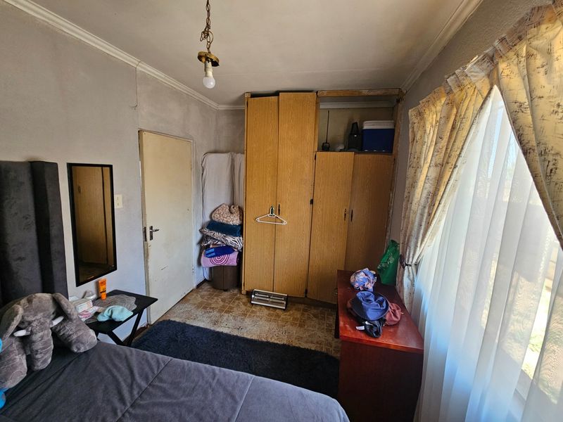 A bedroom featuring a built-in wardrobe, coving, and vinyl flooring. The room requires cosmetic updates and maintenance to improve its overall condition.