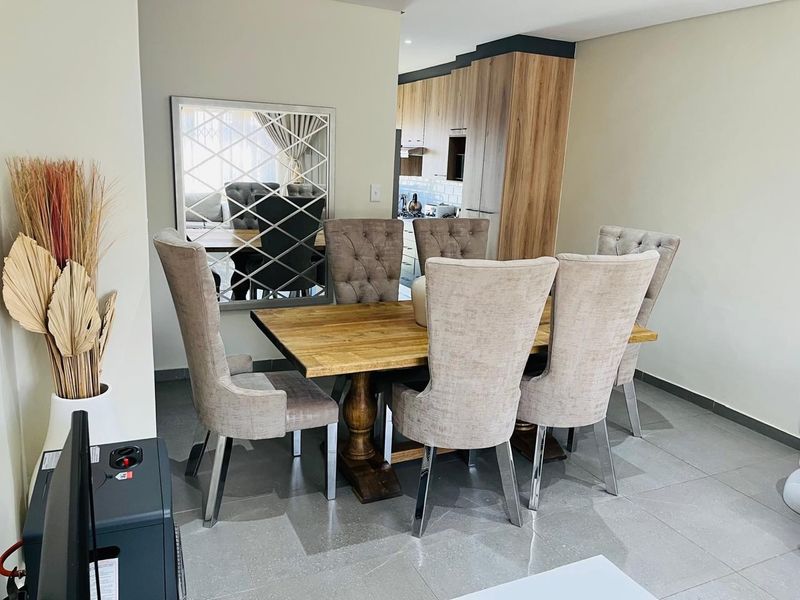 Open plan dining area featuring modern tiled flooring, seamlessly flowing into a contemporary kitchen with wood-finish cabinetry.