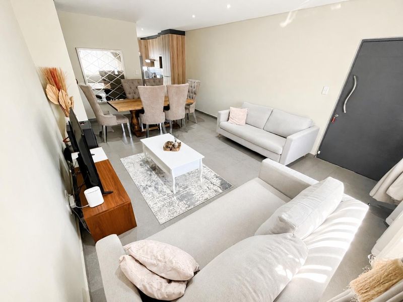 An open-plan living and dining area featuring modern tiled flooring, recessed lighting, and a seamless transition to the adjacent kitchen space.