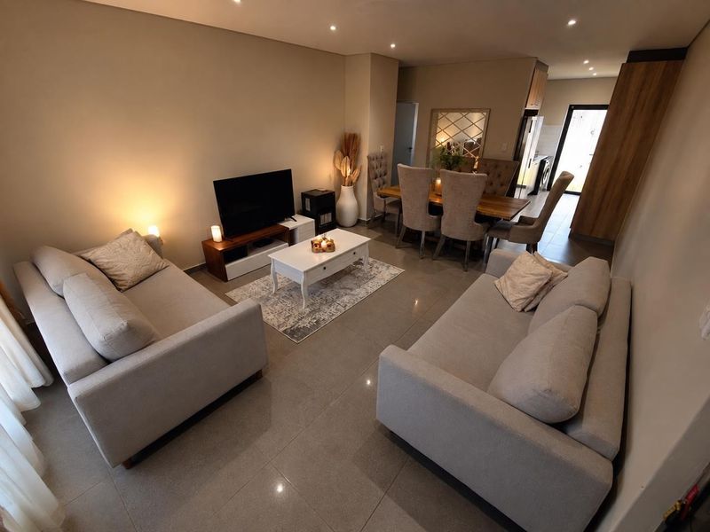 An open-plan living and dining area featuring modern tiled flooring and recessed downlighting, creating a cohesive and functional space.