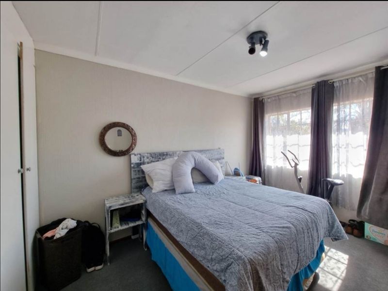 A functional bedroom featuring a built-in cupboard and natural light from the window, providing a comfortable space for rest.