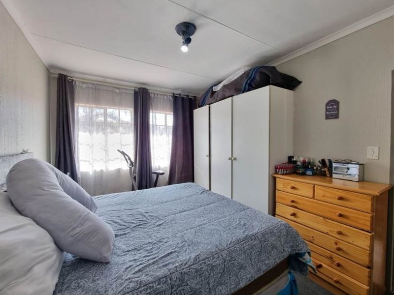 A functional bedroom featuring a built-in wardrobe and natural light through the window.
