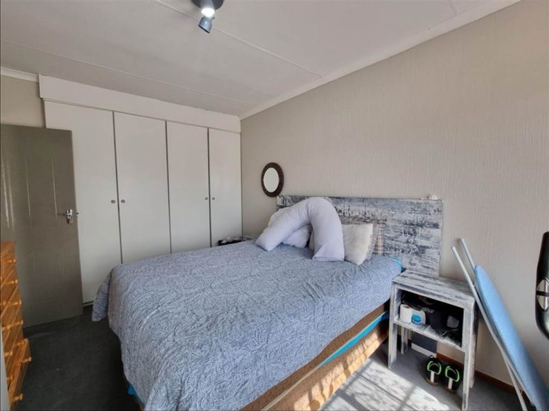 A functional bedroom featuring built-in cupboards and neutral wall finishes, providing a practical space with standard residential fixtures.