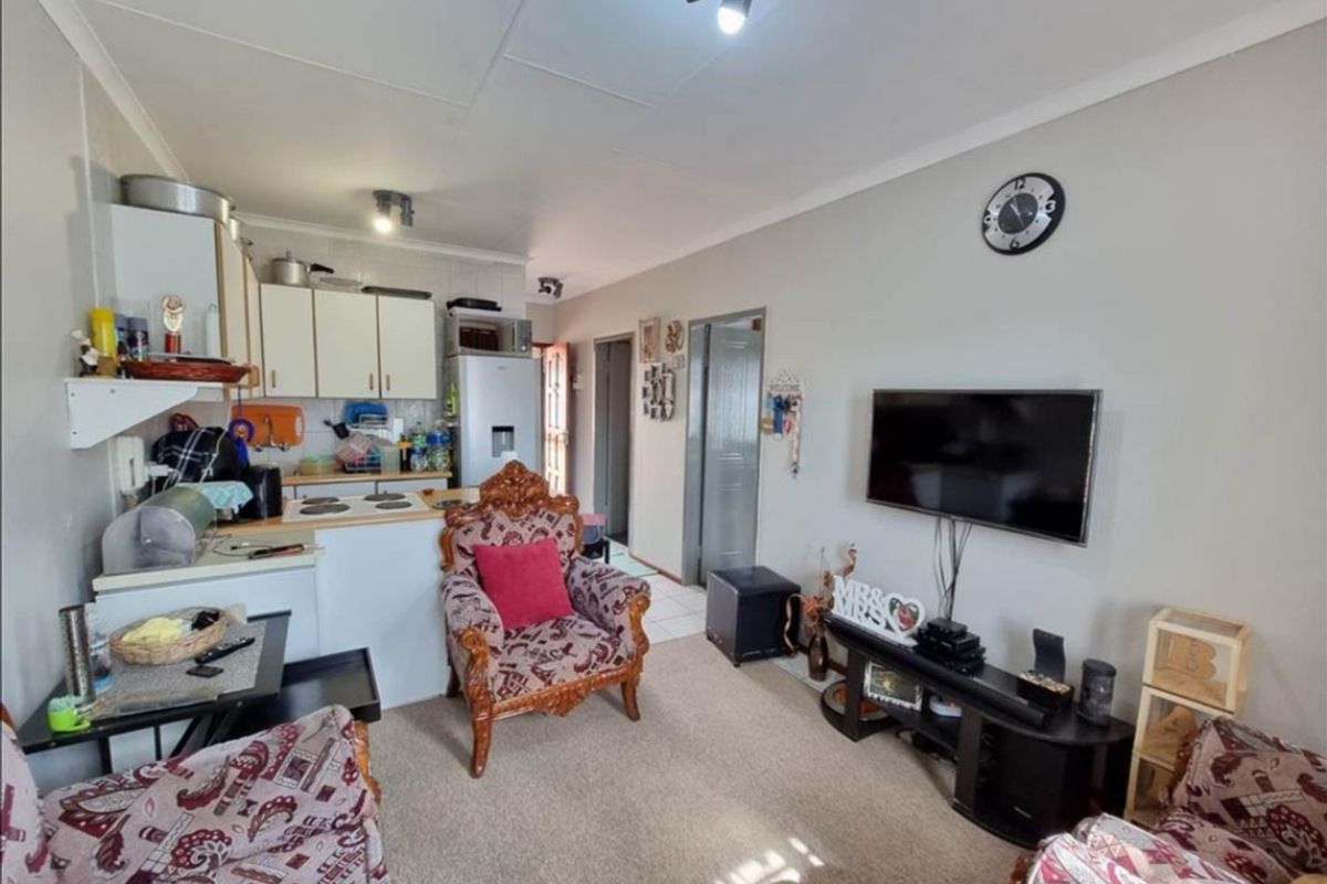 Open-plan living area featuring a compact kitchen with built-in cabinetry and electric hob, seamlessly flowing into the lounge space.