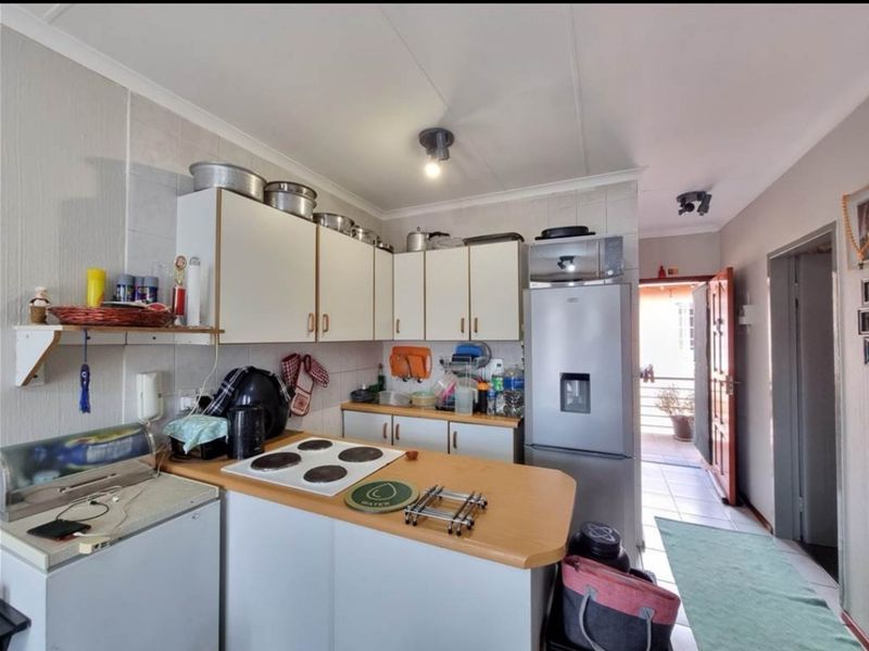 A functional kitchen featuring built-in cabinetry, laminate countertops, and an electric hob, with direct access to an outdoor area.