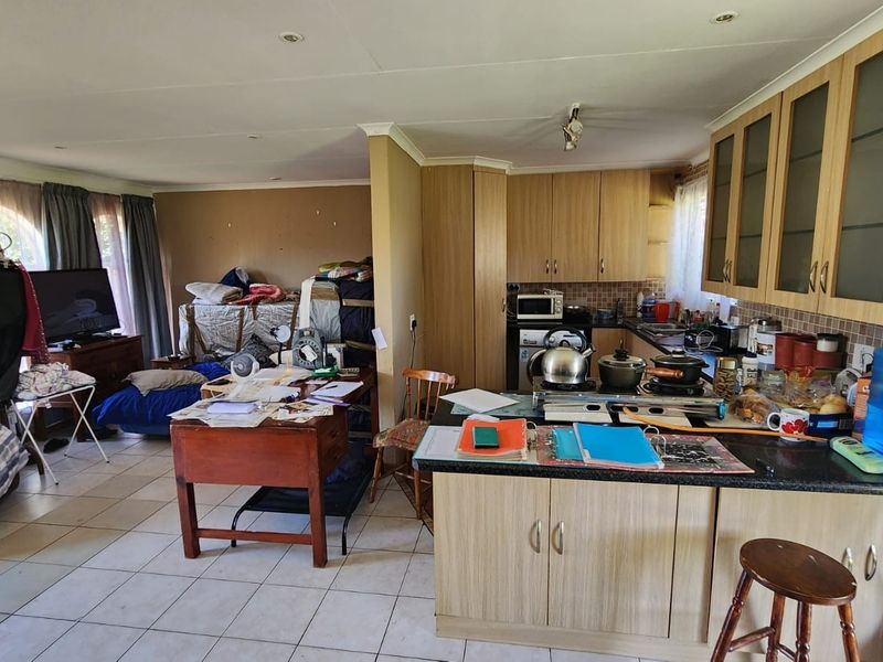 Open-plan living and kitchen area featuring tiled flooring, laminate cabinetry, and granite countertops, offering a functional layout with potential for modernization.