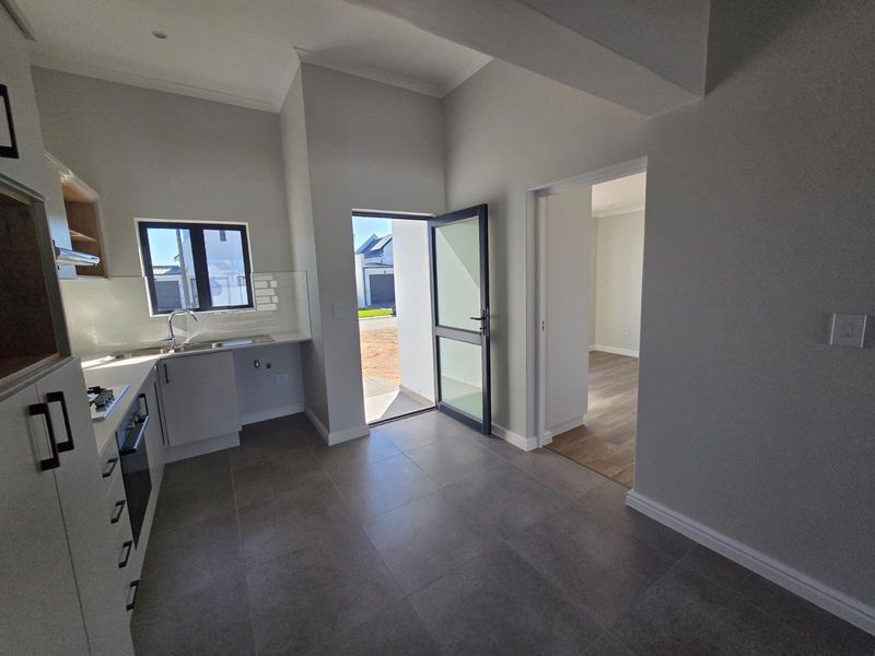 Modern kitchen featuring sleek built-in cabinetry, tiled flooring, and direct access to the exterior, offering a clean and functional workspace.