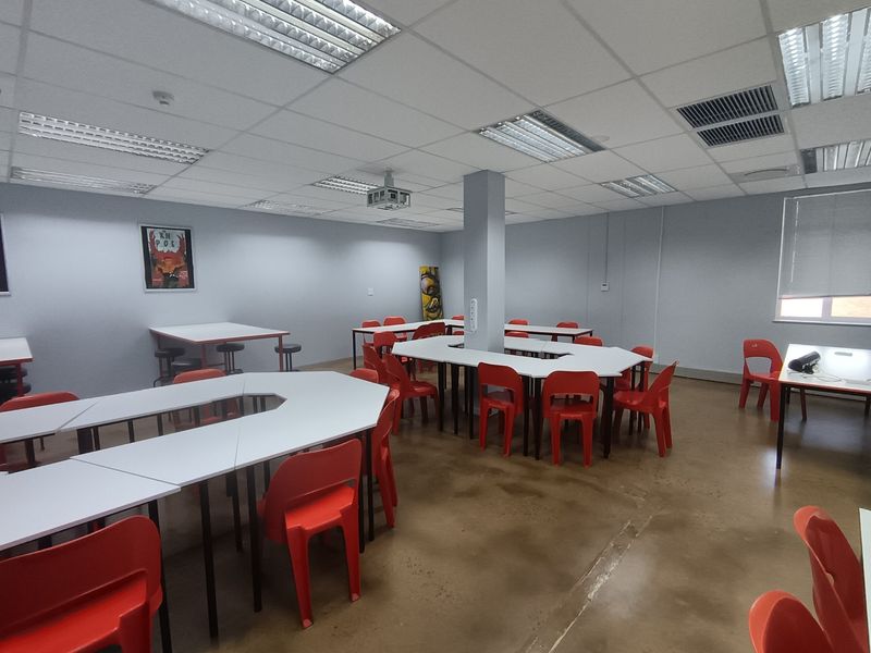 A spacious office or training room featuring a suspended ceiling with recessed lighting, a ceiling-mounted projector, and polished concrete flooring.