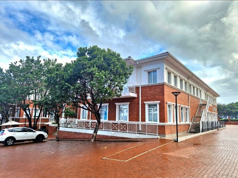 A well-maintained multi-story office building featuring a classic brick facade, external staircase access, and paved exterior grounds.